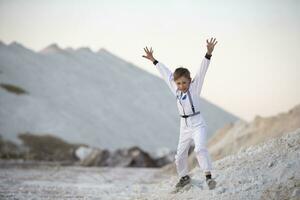 ung pojke i en kostym av ett amerikan astronaut hoppar mot en bakgrund av vit berg. foto
