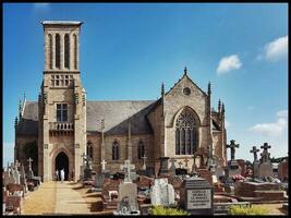 sten kyrka av louannec med kyrkogård i förgrund, Bretagne, Frankrike foto