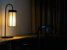 lysande skrivbord lampa på trä- tabell i de mörk sovrum foto
