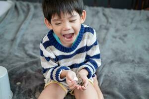 asiatisk pojke lyckligt räkning mynt till spara pengar foto