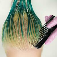 hög-vinkel skott av hårstylist kammande våt grön och missfärgad hår medan schamponering foto