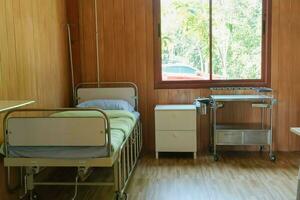 medicinsk professionell arbetsyta med tabell och först hjälpa Utrustning placerad bredvid de sjukhus säng i de rum. medicin och sjukvård begrepp foto