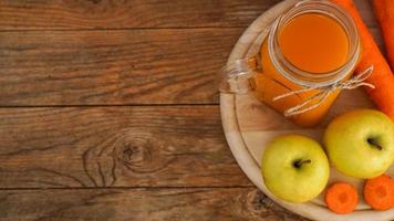 äpple- och morotsjuice i glas, färska grönsaker och frukter på trä foto