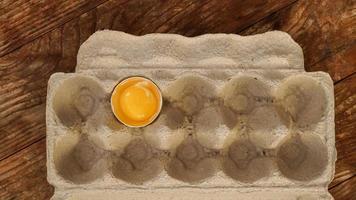 ett trasigt ägg i en äggbricka i kartong. halvt ägg foto