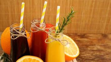 hemgjord limonad i små flaskor. mångfärgade juicer och frukter foto