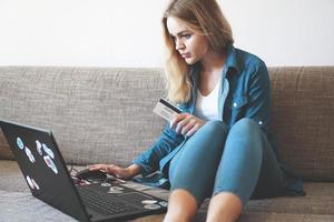 ung vacker kvinna som arbetar med bärbar dator och kreditkort hemma foto
