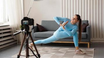 kvinna bloggare i sportkläder skjuter video på kameran hemma