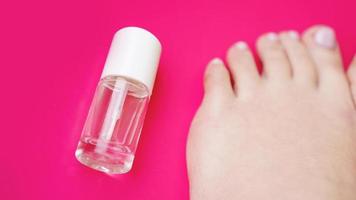 pedikyr med transparent nagellack på rosa bakgrund foto