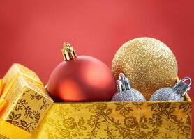jul röd, guld, silver- bollar i öppen gul låda på röd bakgrund. ny år dekor. kopia Plats foto