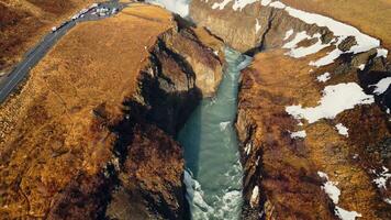 antenn se av gullfoss flod vattenfall, skön kall vatten strömmande mellan frysta snöig kullar och fält. isländsk natur och nordic landskap nära kaskad. långsam rörelse. foto