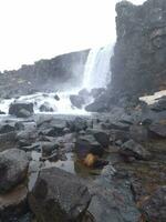 gullfoss vattenfall i nordic landskap, majestätisk isländsk landskap med snöig kullar och isig vatten faller av klippa. flod ström på topp av frostig sten berg, scandinavian kaskad nära dal. foto