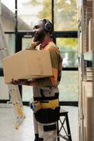 lager arbetstagare innehav kartong lådor lyssnande musik på hörlurar, framställning klienter order under arbete flytta i lagring rum. afrikansk amerikan anställd arbetssätt på Produkter sändning foto