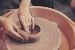 närbild kvinna händer arbetssätt hantverk på krukmakeri hjul framställning lera pott terrakotta. foto