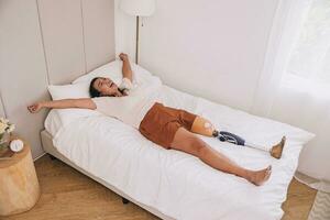 Lycklig kvinna protetik bion ben vakna i de morgon- på härlig Hem säng sorglös stark friska Bra mental foto