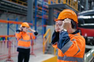 ingenjör team arbetstagare kolla upp säkerhet hjälm Kläder för arbete elektrisk tåg service depå transport industri fabrik tekniker mekaniker personal. foto