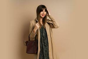 eleganta brunett kvinna bär trendig täcka , Framställ över beige bakgrund. vinter- mode trender. foto