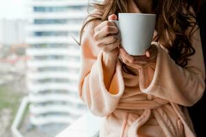 kvinna i morgonrock innehav kopp av varm te. utfall humör. foto