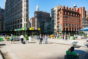 ny york stad, USA - augusti 9, 2019-människor promenader bland de känd skyskrapa kallad fatiron byggnad i manhattan under en solig dag foto