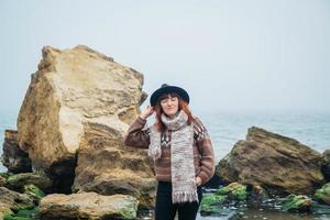 kvinna turist i hatt med ryggsäck på stenar på en bakgrund av havet