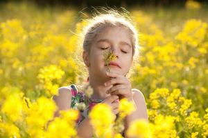 liten flicka njuter av lukten av blommor foto