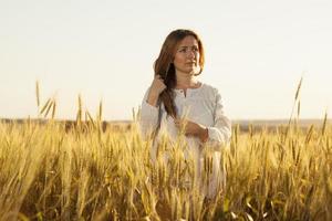 ung kvinna står mitt i ett vetefält