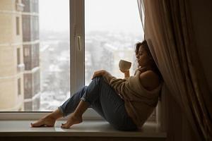 kvinna vid fönstret som dricker kaffe foto