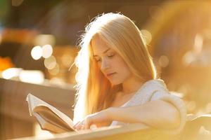 glad blond tjej som läser en bok foto
