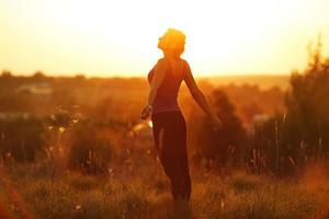 glad kvinna i ett fält vid solnedgången