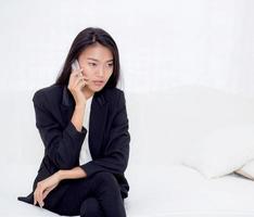 ung asiatisk kvinna som talar telefon i vardagsrummet. foto