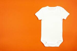 vit bebis flicka eller pojke kroppsdräkt attrapp platt lägga på orange bakgrund. design onesie mall, skriva ut presentation falsk upp. topp se. foto