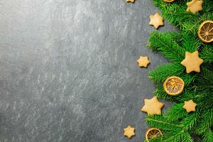 jul traditionell pepparkaka stjärnor med dekoration, kryddor och jul träd grenar på en mörk sten bakgrund. topp se. kopia Plats. foto