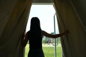 en kvinna turist öppnas de gardiner och utseende på de landskap. foto
