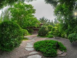 små japansk trädgård parkera stil i vår med träd och trä- hus på djup trädgård. de sten väg till de hus. foto