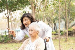 läkare hjälp asiatisk senior kvinna patient sitter på rullstol foto