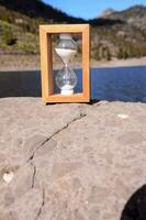 en trä- timglas Sammanträde på de kant av en sjö foto