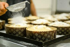 kock producerar panettone, medan lugna, tillsats mandel socker garnering till rå ljuv bröd. foto