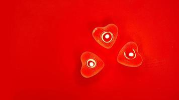 tre röda brinnande ljus med hjärtformade dekorationer foto