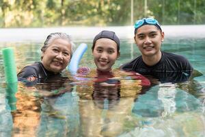 ung tränare portion senior kvinna i aqua aerobics och arbetssätt ut i de slå samman. gammal kvinna och mogna man håller på med aqua aerobics övning i simning slå samman, äldre sporter, och aktiva livsstil begrepp. foto