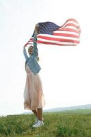 en flicka i en korallklänning och en jeansjacka håller USA: s flagga foto