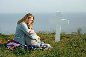 mamma och son sitter på en soldats grav foto