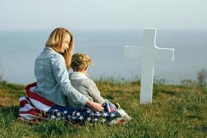 mamma och son sitter på en soldats grav