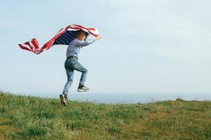 en liten pojke springer med USA: s flagga