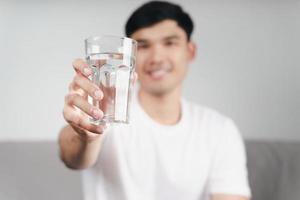 man dricker ett glas vatten i soffan i vardagsrummet. foto