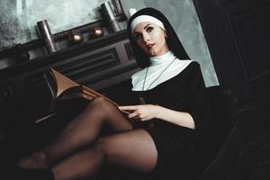 vacker ung nunna i religion svart kostym håller bibeln. religion foto
