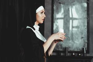 ung katolsk nunna håller ljus i sina händer foto