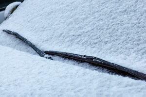 snö täckt bil vindskydd, vindrutetorkare och hätta foto