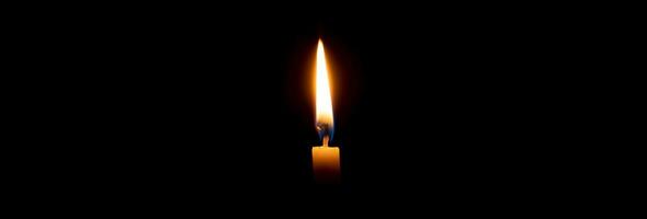 enda brinnande ljus flamma eller ljus lysande på en små gul ljus på svart eller mörk bakgrund på tabell i kyrka för jul, begravning eller minnesmärke service med kopia Plats. foto