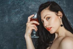 vacker kvinna med ett glas vin på grå bakgrund foto