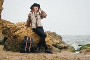 kvinna i en hatt med en ryggsäck på bakgrund av hav och stenar foto