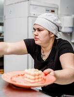 kvinnlig kock som serverar en dessert på pizzeria -köket foto